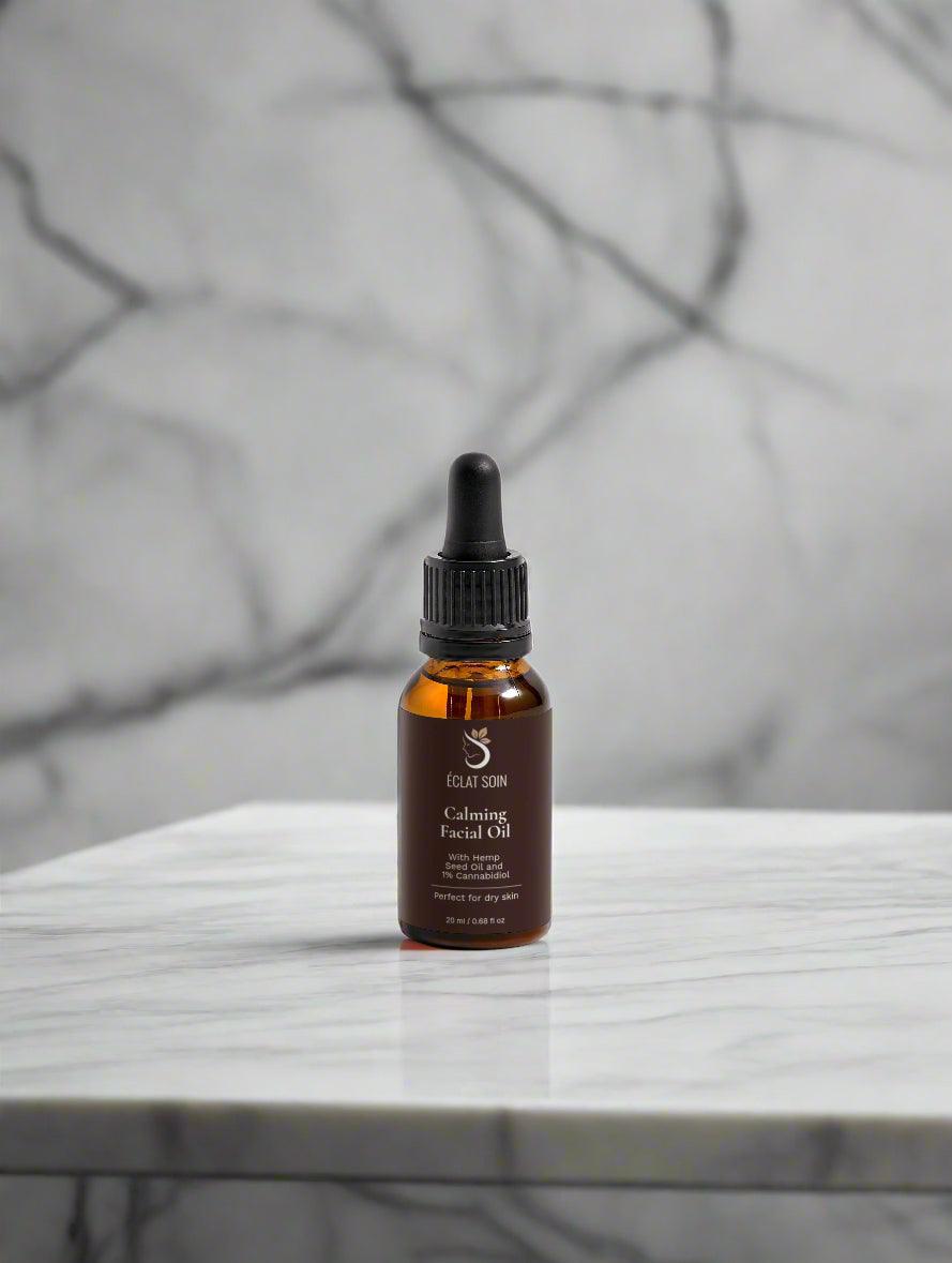 Eclat Soin Calming Facial Oil with Cannabidiol in a brown glass dropper bottle on a marble surface
